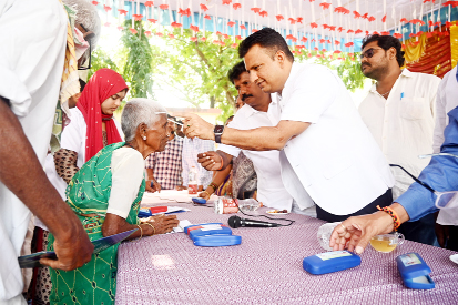 వృద్ధురాలికి కంటి అద్దాలు అందజేస్తున్న కలెక్టర్‌