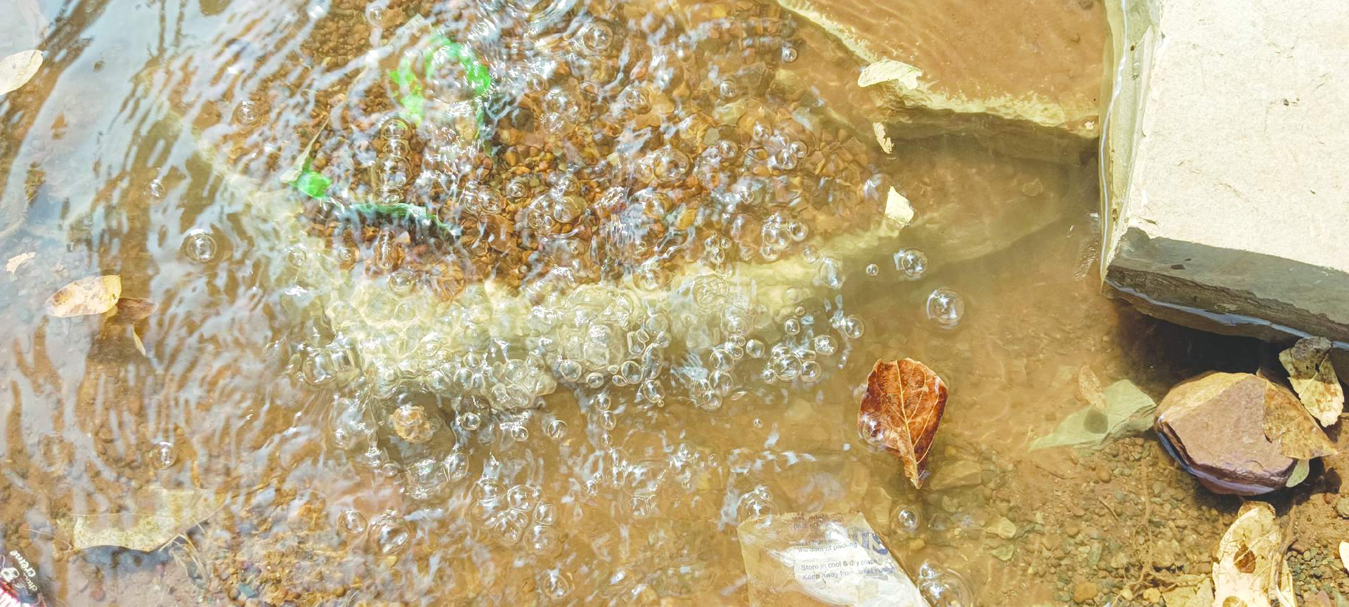 జడ్పి పాఠశాల ప్రధాన గేటు వద్ద లీకైన పైపులైన్‌ దృశ్యం